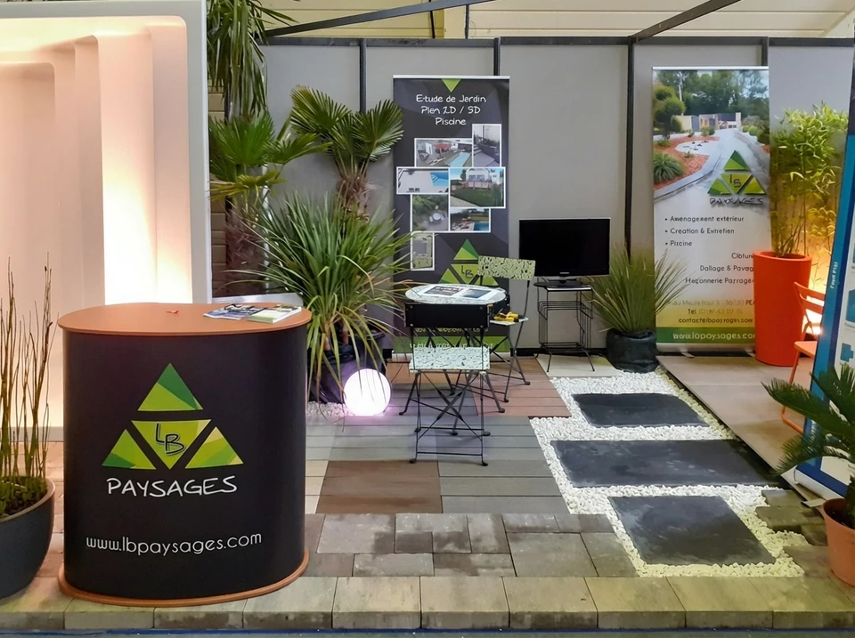 Terrasse extérieure en dalles de pierre naturelle avec salon de jardin en résine tressée anthracite comprenant deux fauteuils coques avec coussins blancs et table basse ronde